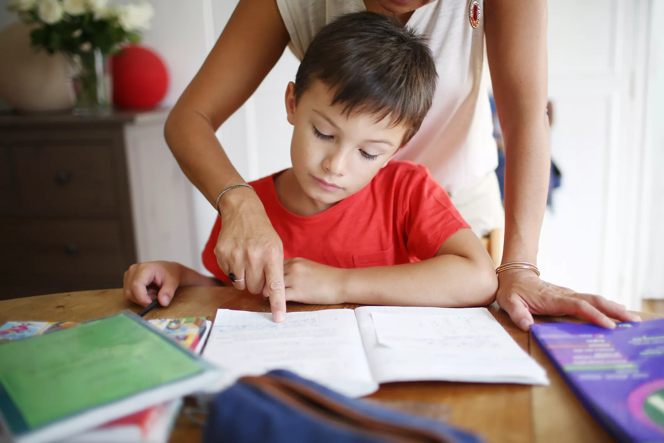 Mom guides boy in doing his homework.
