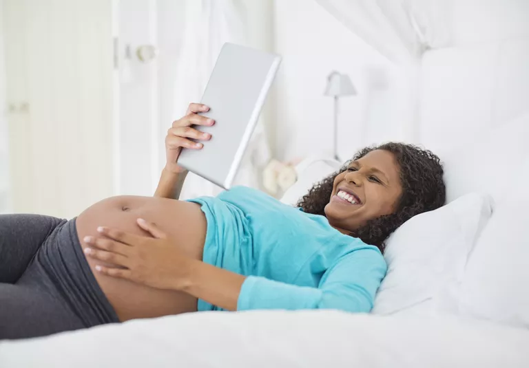 Hamile kadın yatakta tablet bilgisayar kullanarak