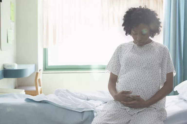 Midesini hastanede tutan hamile Afrikalı-Amerikalı kadın